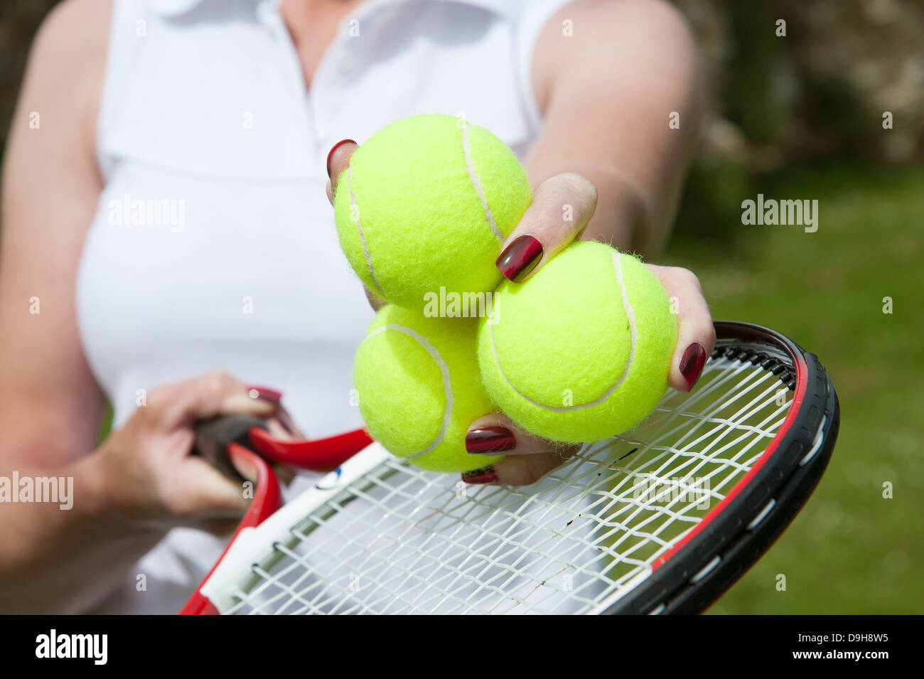 Tennis balls in a player's hand above racquet strings Stock Photo Alamy