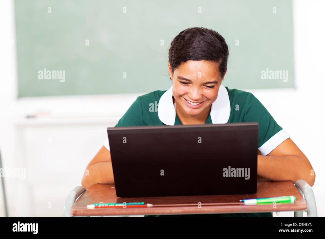 female high school student using laptop in classroom Stock Photo