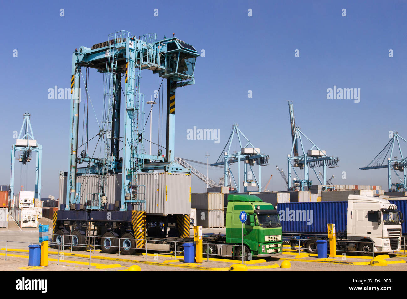 Mobile container spreader placing a container on a truck trailer in a large port. Stock Photo