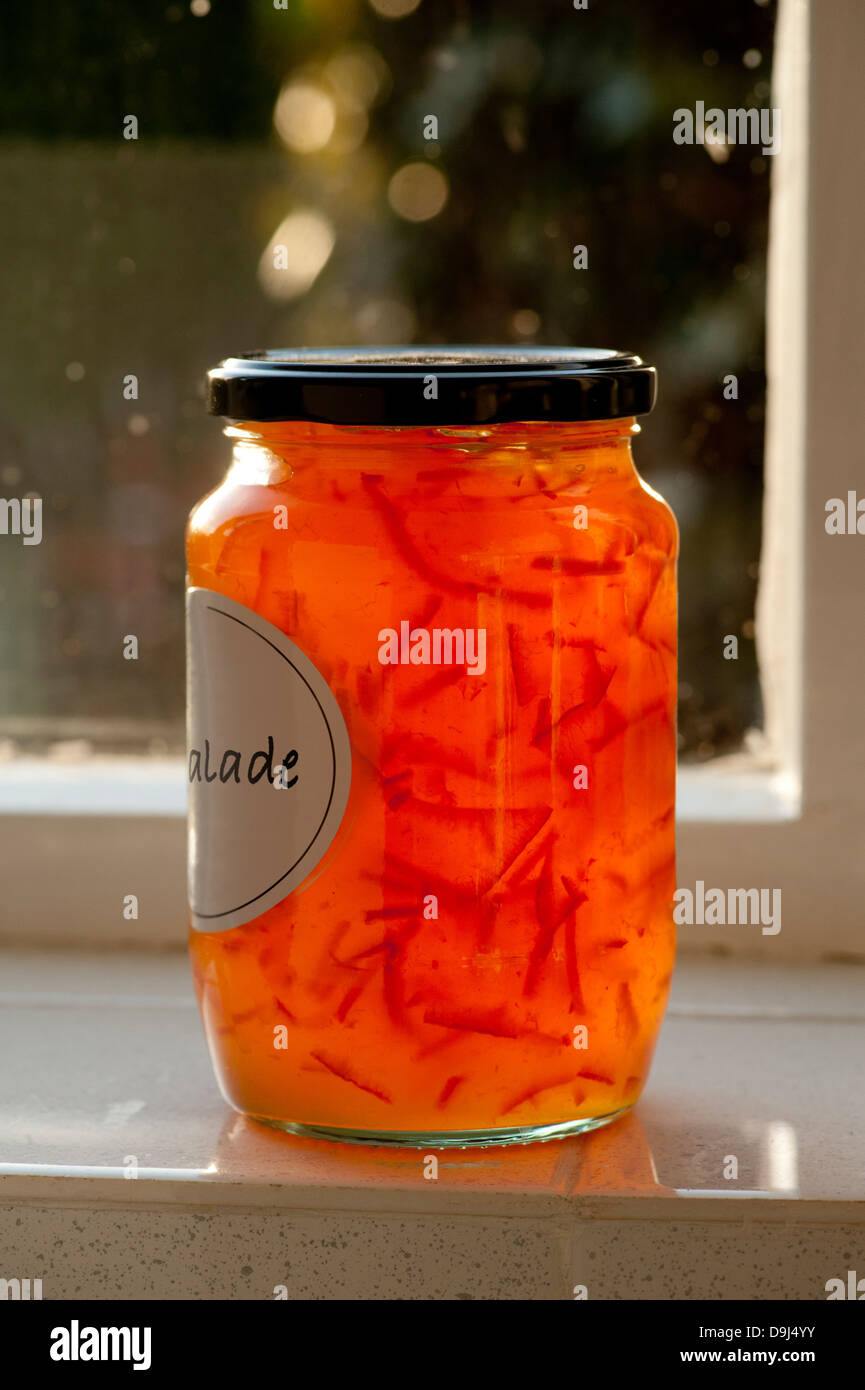 Backlit marmalade with label partially showing to reveal strands of orange peel. No visible branding. Stock Photo