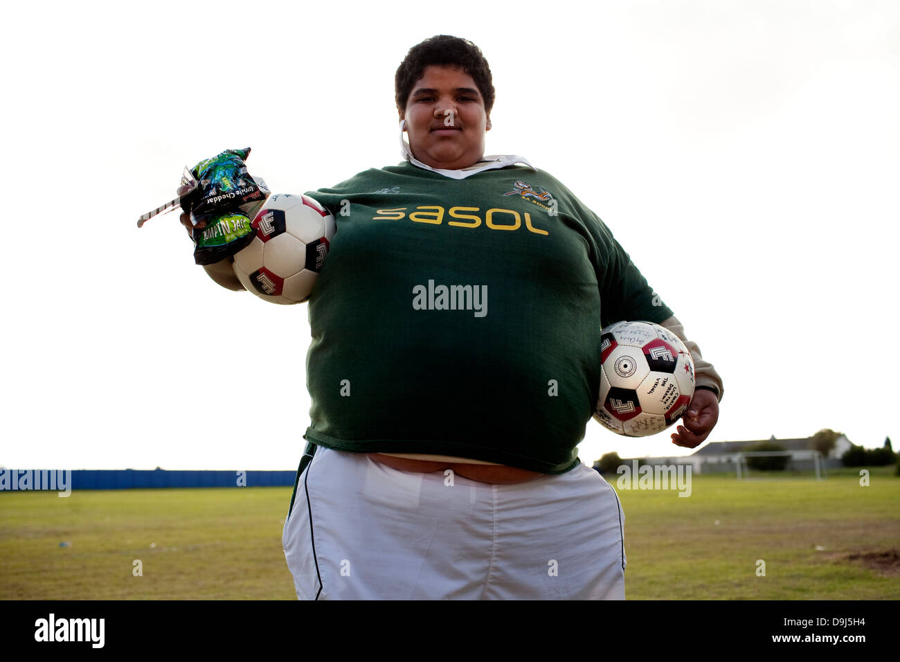 A portrait football player holding two footballs wearing South African rugby shirt in Stompneus Bay in Western Cape South Stock Photo