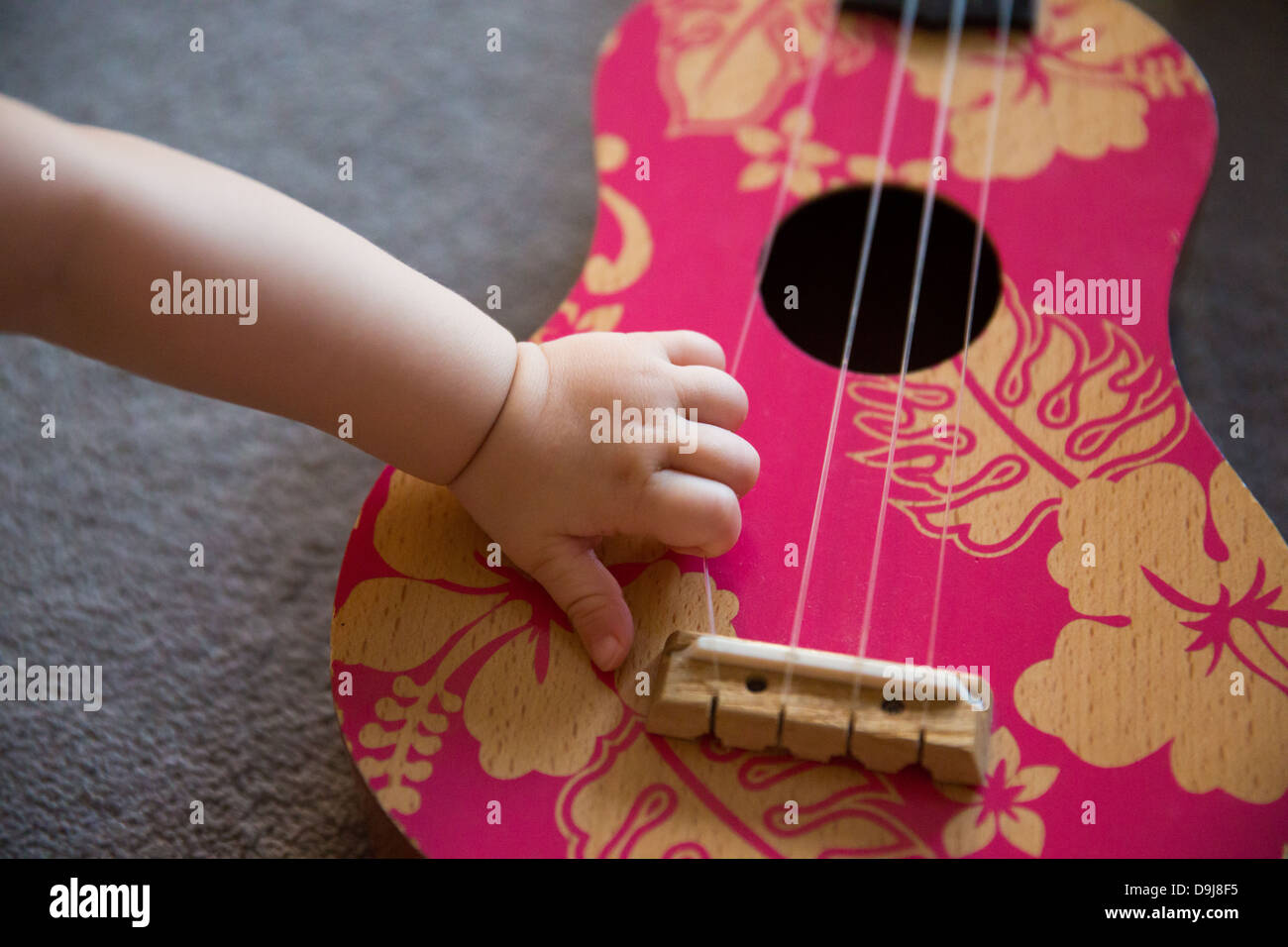 Baby's hand on pink Ukulele Stock Photo Alamy