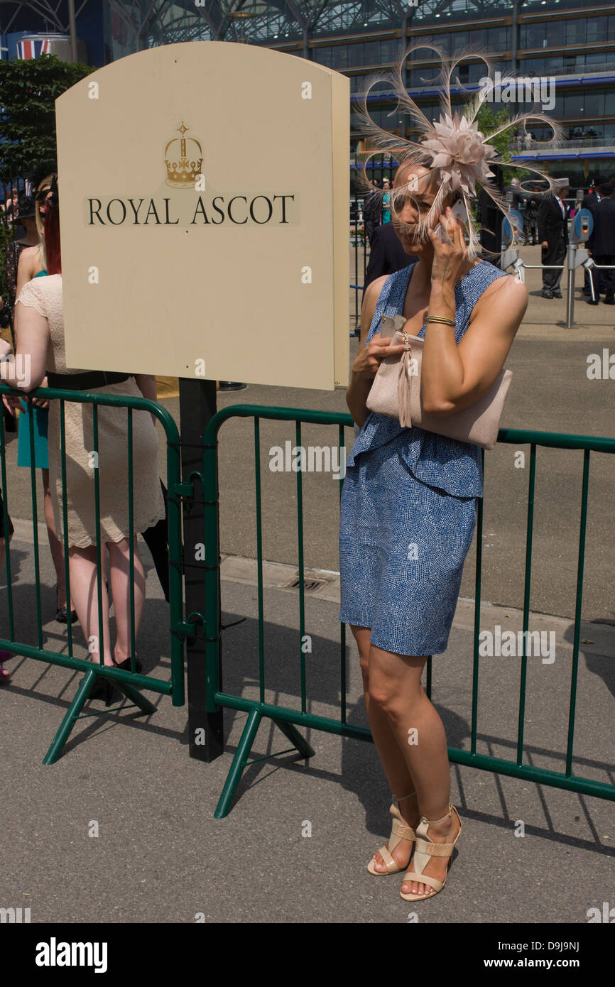Lady wearing an extraordinary hat makes a call on her smartphone during the annual Royal Ascot horseracing festival in Berkshire, England. Royal Ascot is one of Europe's most famous race meetings, and dates back to 1711. Queen Elizabeth and various members of the British Royal Family attend. Held every June, it's one of the main dates on the English sporting calendar and summer social season. Over 300,000 people make the annual visit to Berkshire during Royal Ascot week, making this Europe’s best-attended race meeting with over £3m prize money to be won. Stock Photo
