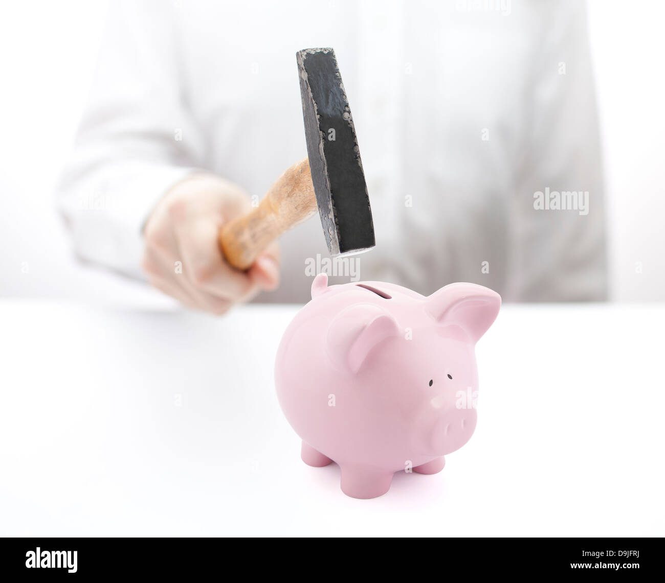 Pink piggy bank and hand with hammer Stock Photo - Alamy