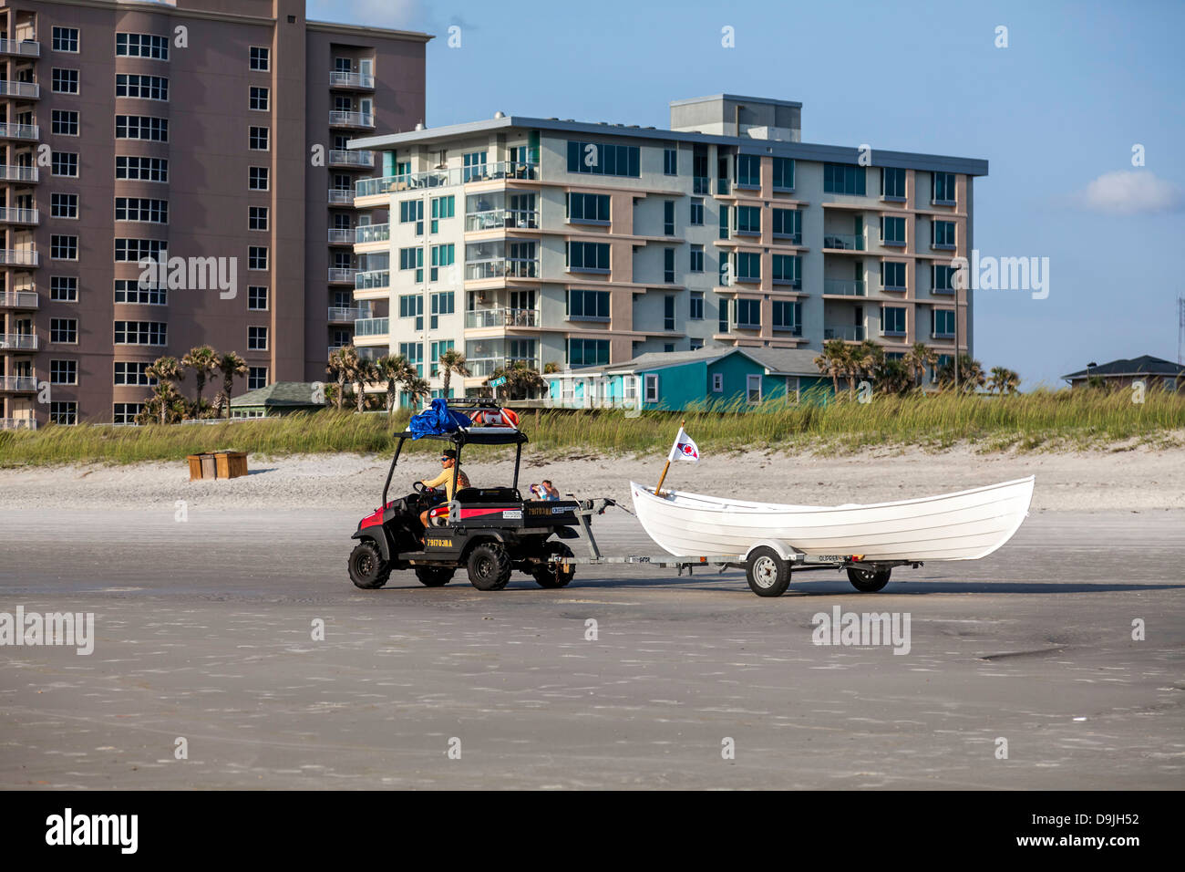 The Jacksonville Beach Red Cross volunteer beach rescue boat being towed down to the ocean by a man driving a beach buggy. Stock Photo
