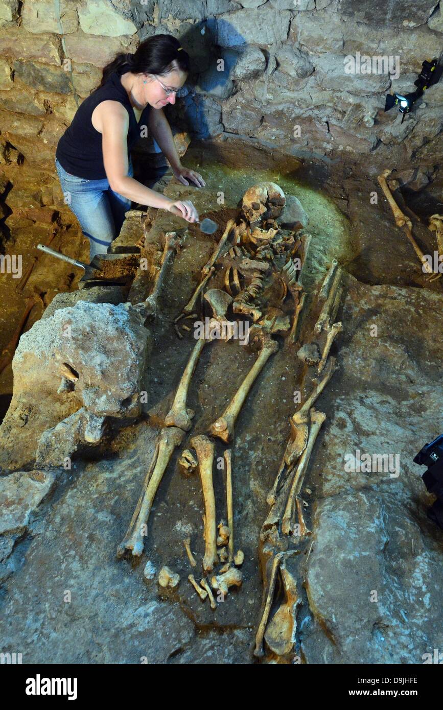 Walldorf, Germany. 20th June, 2013. Dig director Regina Frimel uncovers a skeleton in a grave during an archaeological excavation in the church in Walldorf, Germany, 20 June 2013. More than 30 graves have been discovered during renovation work. On 03 April 2012, the fortified church, whose history extends back into the Middle Ages, went up in flames. The steeple should be reconstructed by the end of the year and the rest of the church in three to four years. Photo: MARTIN SCHUTT/dpa/Alamy Live News Stock Photo