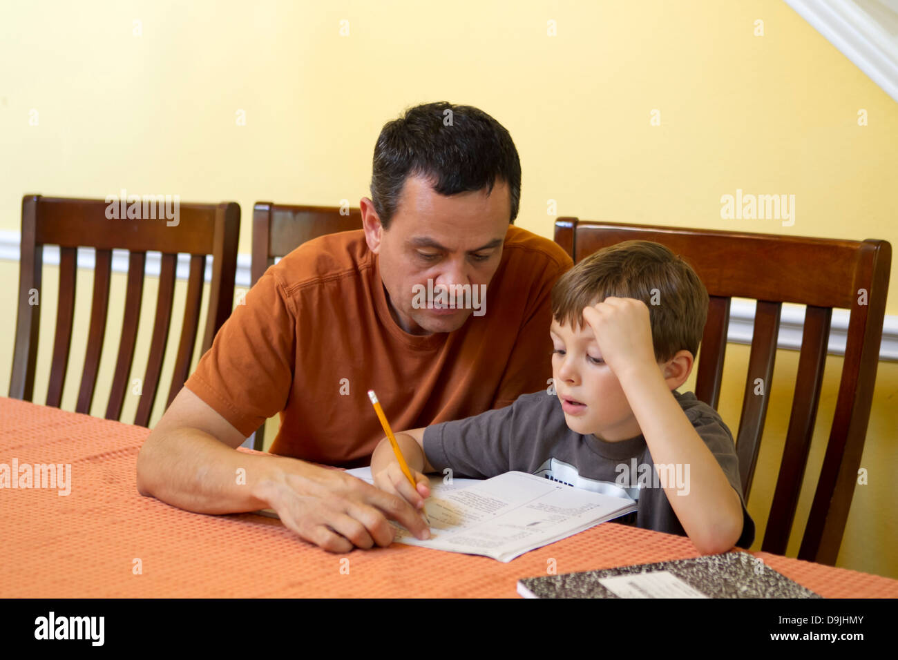 Mexican-American father ( 50 year old) helps out his Hispanic 7 year old son with homework Stock Photo