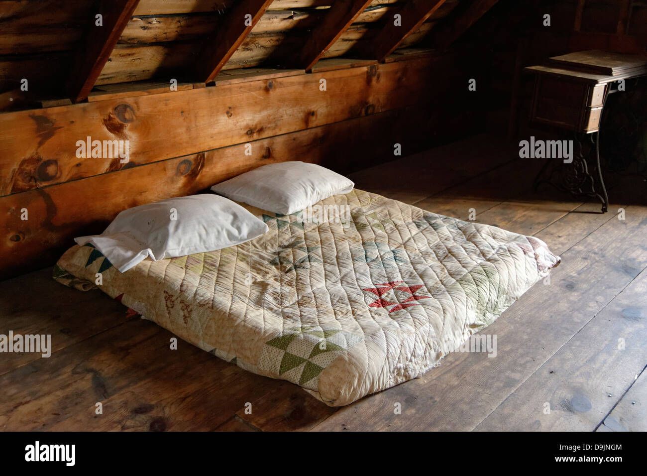 Bed wrapped in quilt on floor of attic. Robert Frost farm Derry, New