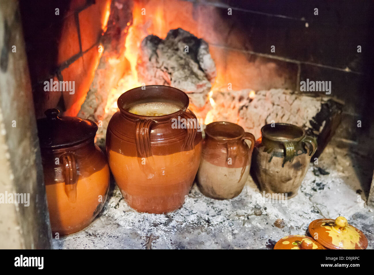 Chickpeas and other pulses in terracotta jars, cooking by an open fire. Stock Photo
