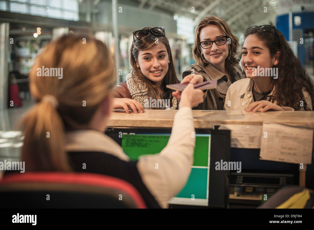 Woman and two teenage girls at airport check in area Stock Photo