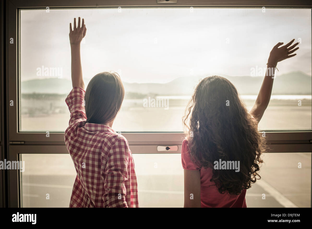 Two teenage girls waving through window Stock Photo