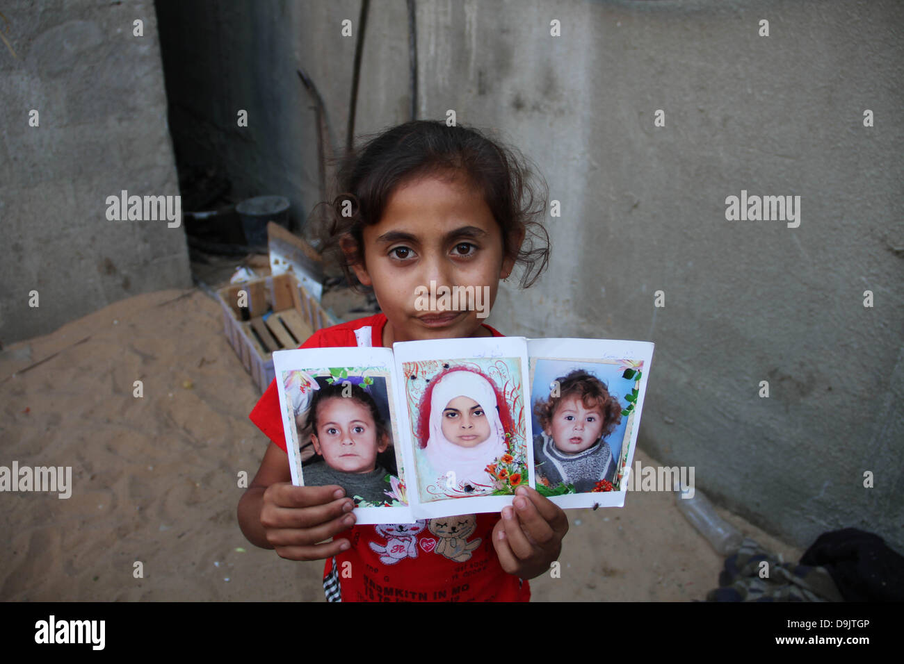 Child suffering from malnutrition and poverty, displays pictures of the siblings of children who were killed by Israel fired a missile at their home in the Gaza war of 2012. Stock Photo