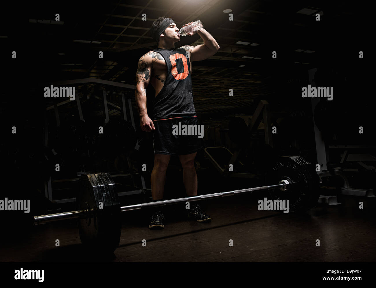 Young man drinking from water bottle in gym Stock Photo - Alamy