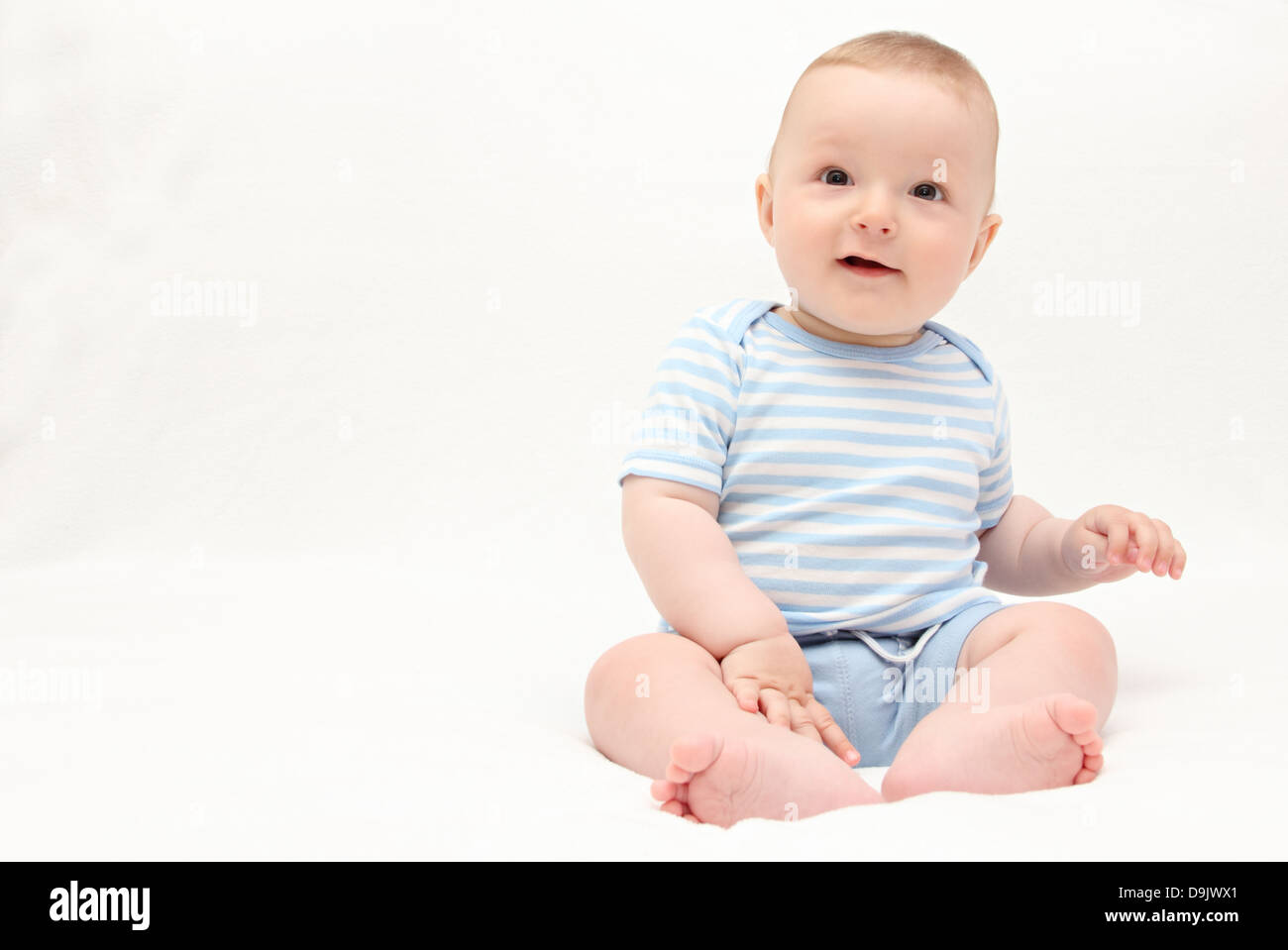 beautiful laughing happy baby boy sitting on white bed Stock Photo