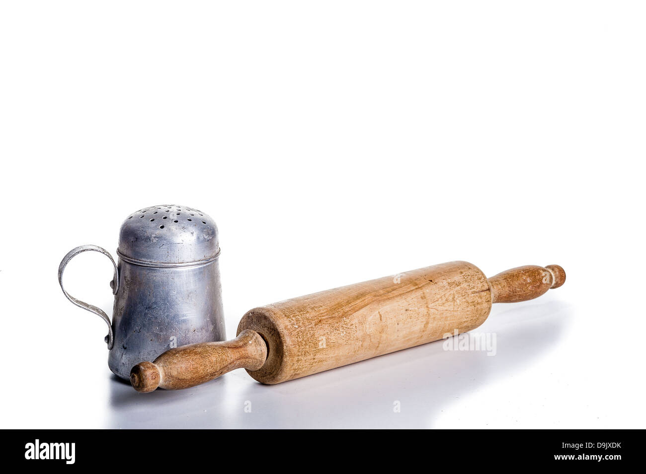 Vintage cooking utensils - salt or sugar shaker and wooden rolling pin - on white; space for text Stock Photo