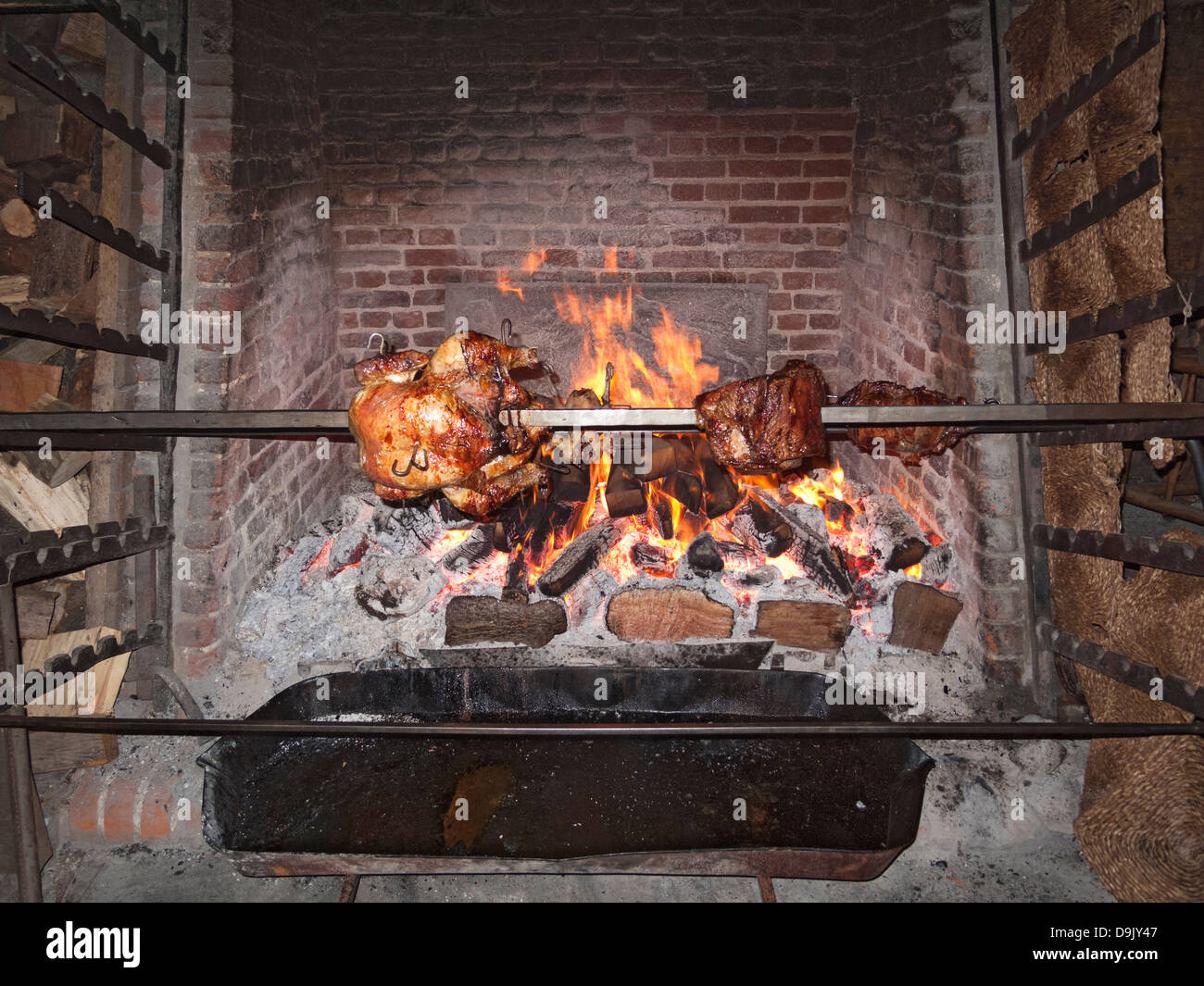 Royal history heritage sightseeing: interior of Hampton Court Palace, chicken and meat being spit roasted in the kitchen over an open fire, UK Stock Photo