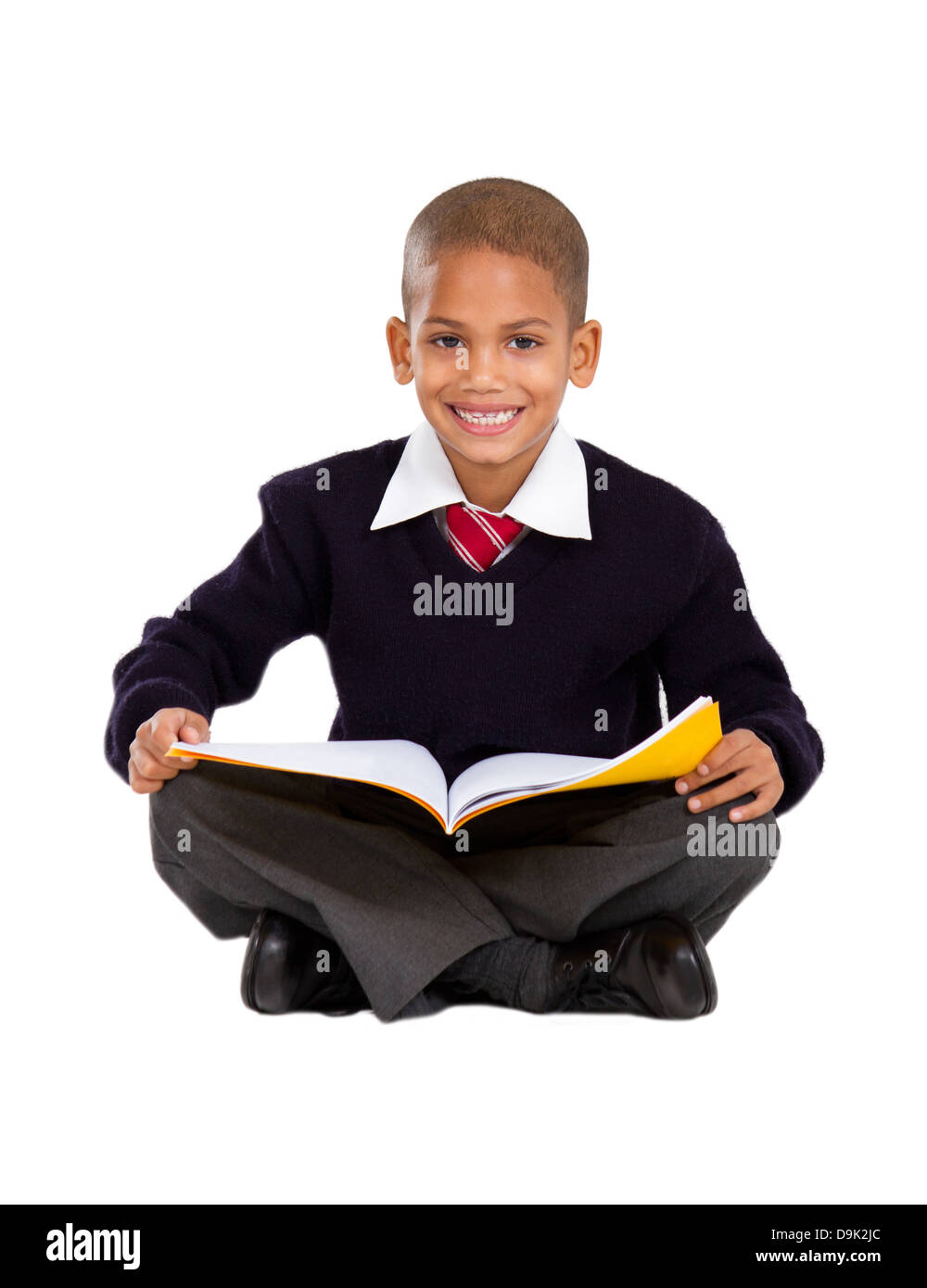 primary schoolboy sitting on floor and reading Stock Photo