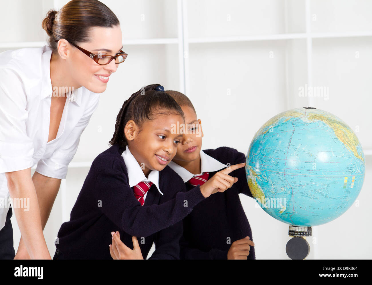 elementary geography teacher and students looking at globe in classroom Stock Photo Alamy