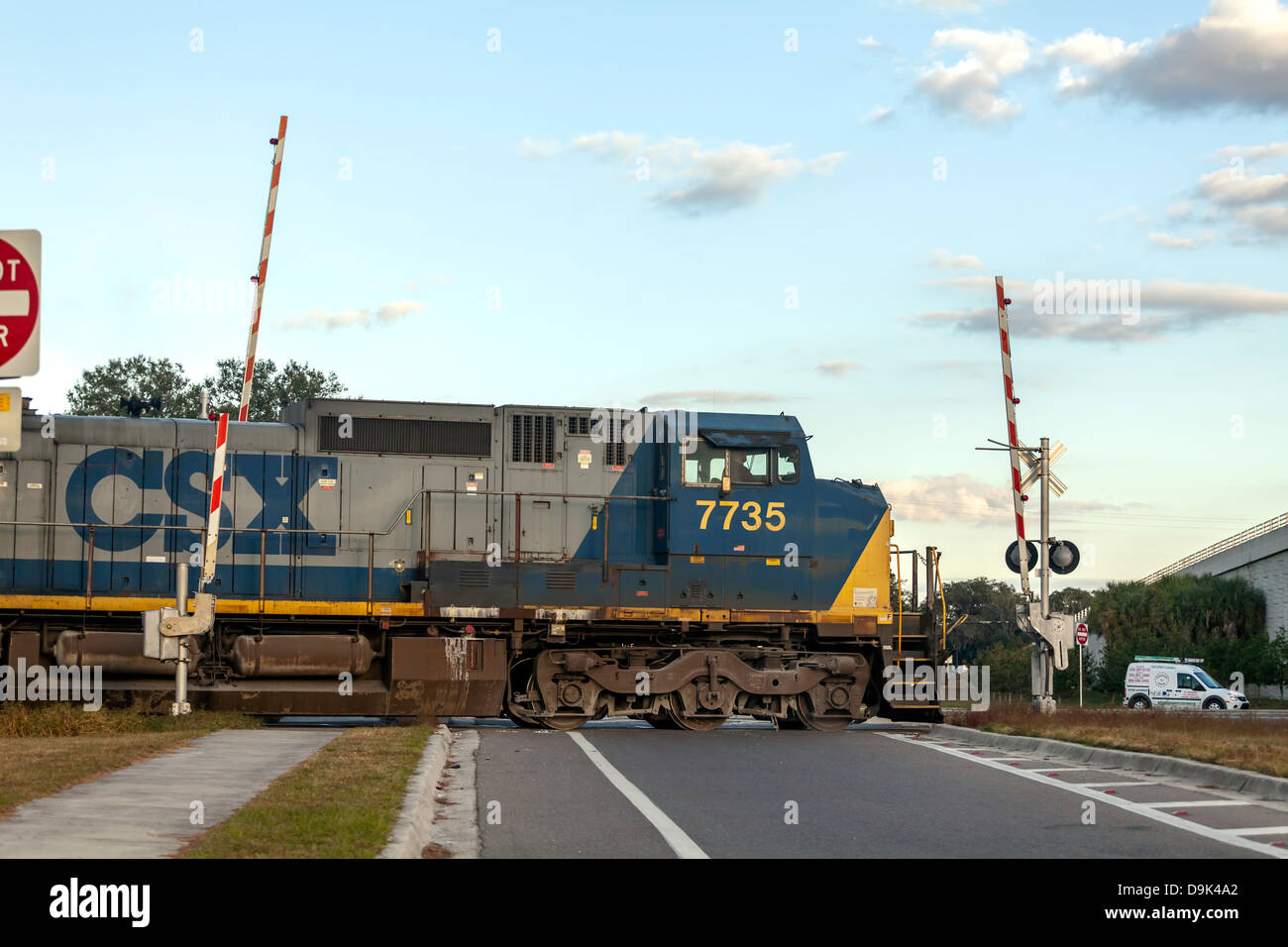CSX engine 7735 pulling a freight train through a railroad crossing in