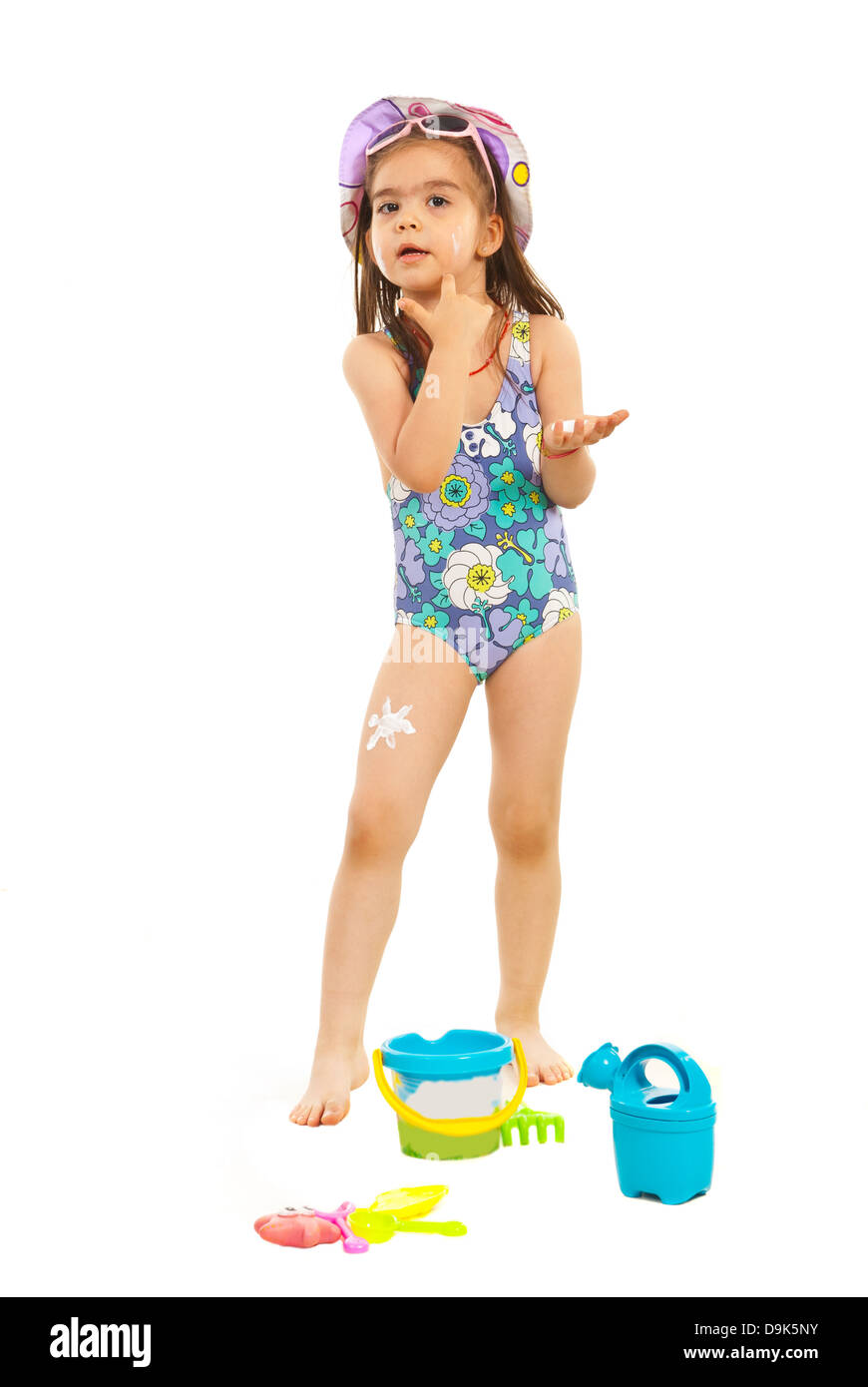 Little girl in swimsuit applying sunscreen lotion on her face isolated