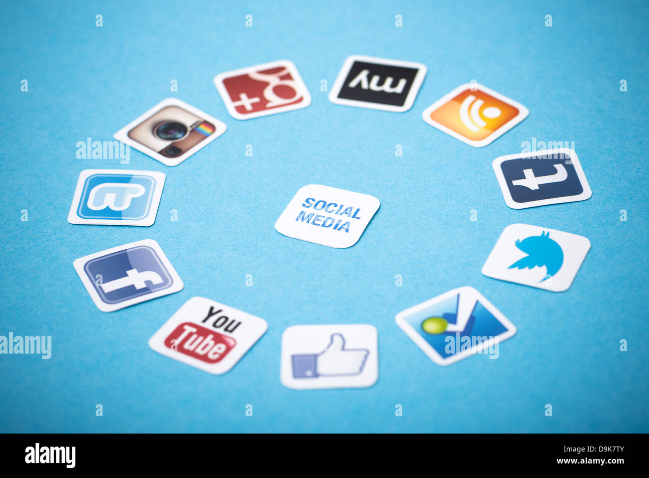 A logotype collection of well-known social media brands printed on paper and placed around on a blue background. Stock Photo