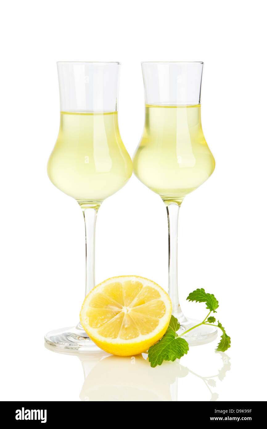 Two glasses of italian Limoncello liqueur, lemon half and lemon balm