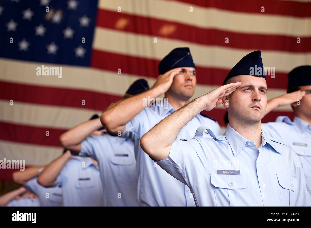 US Air Force Airmen salute to the American flag during the singing of the Star Spangled Banner a change of command ceremony May 13, 2013 at Kadena Air Base, Japan. Stock Photo