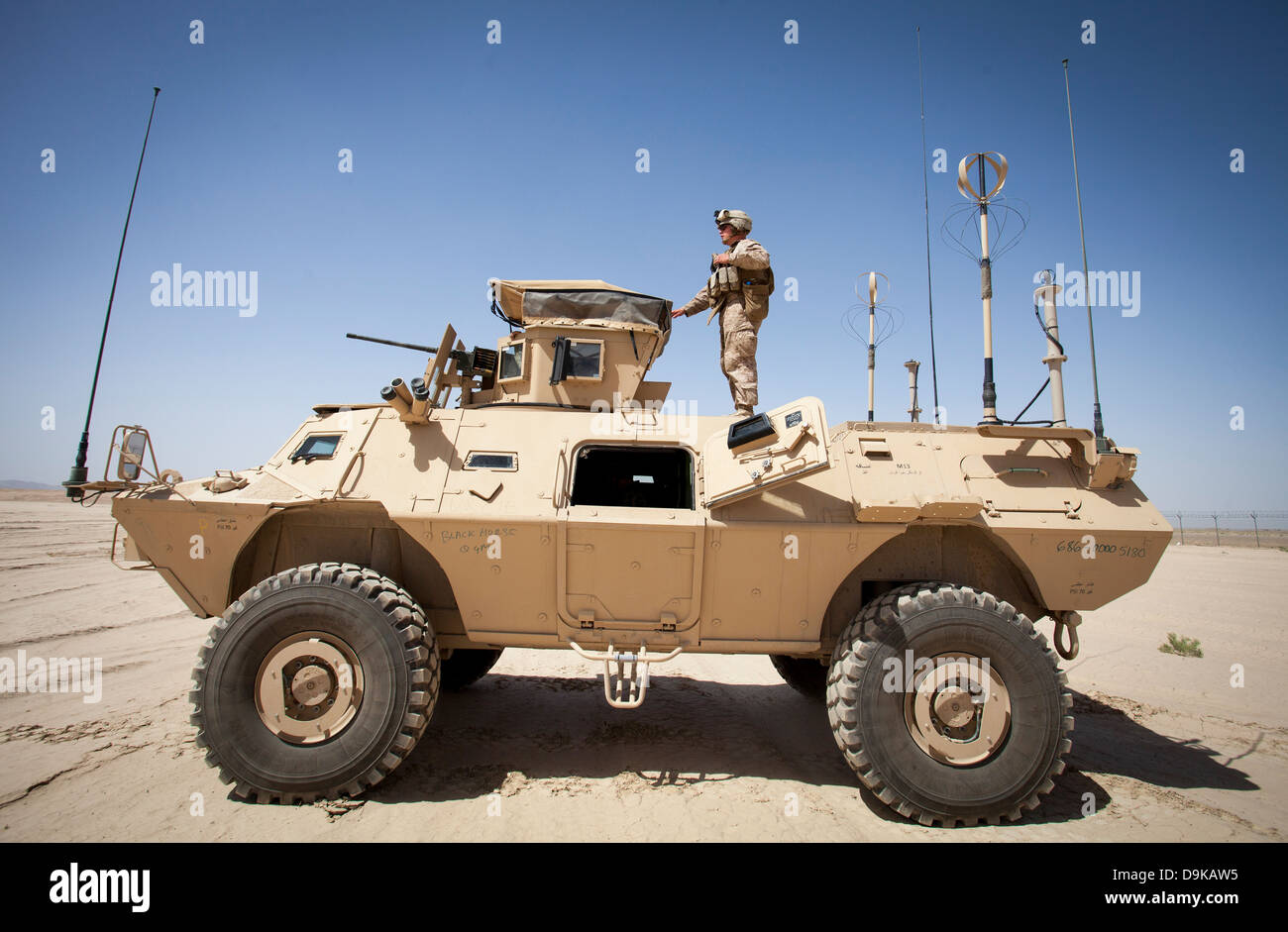 A US Marine Corps advisor stands on a M1117 armored vehicle to observe ...