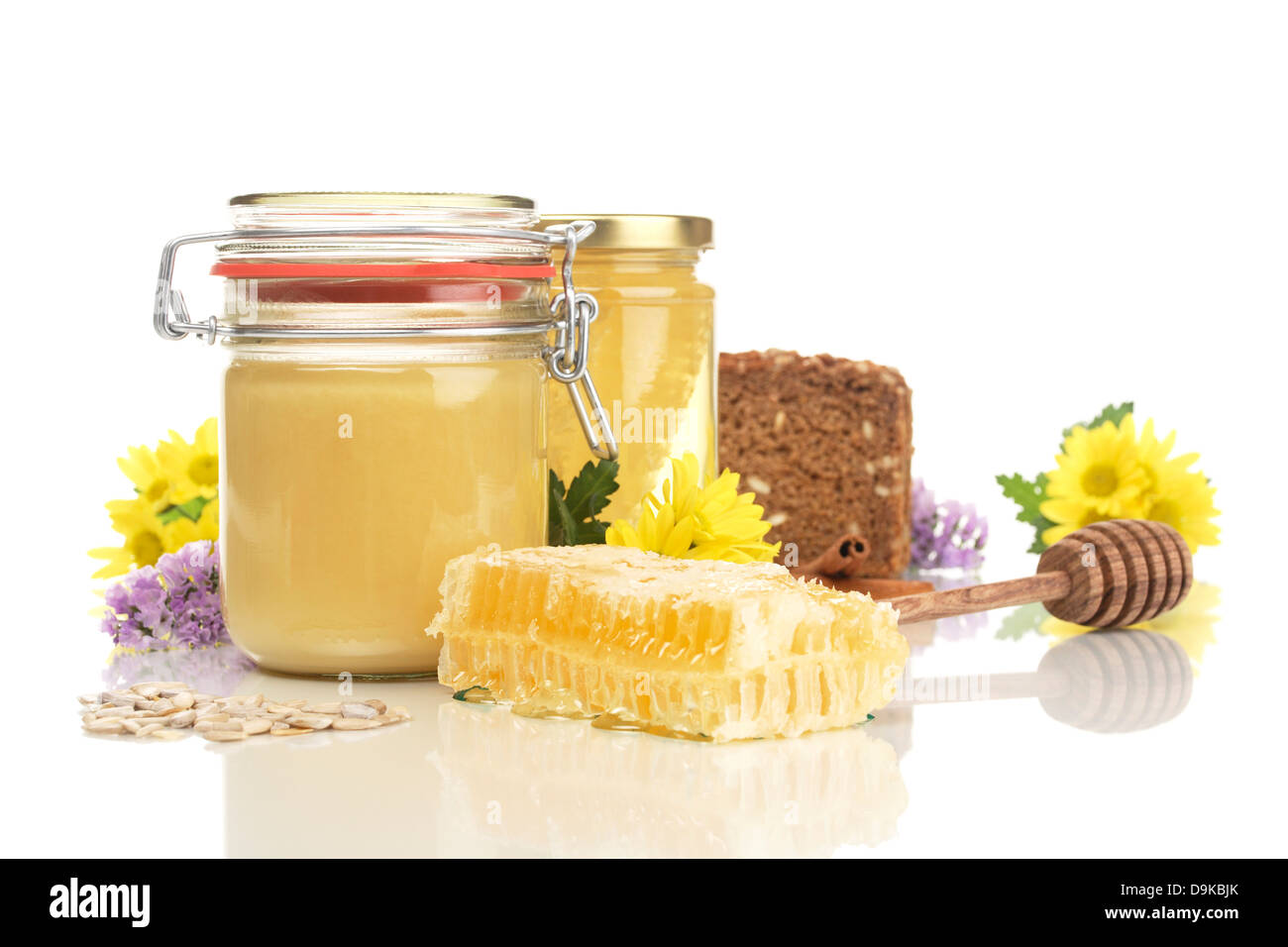 Honey glasses with honeycomb, wholemeal bread, honey spoon, sunflower cores and flowers, Honeycomb jars with honey, wholemeal br Stock Photo