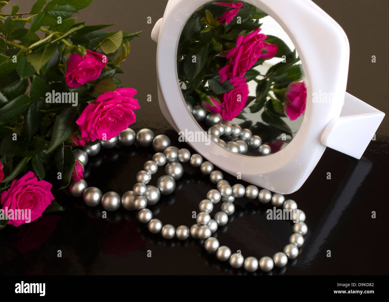 pearl bracelets, bouquet of roses and a mirror on a black background Stock  Photo - Alamy
