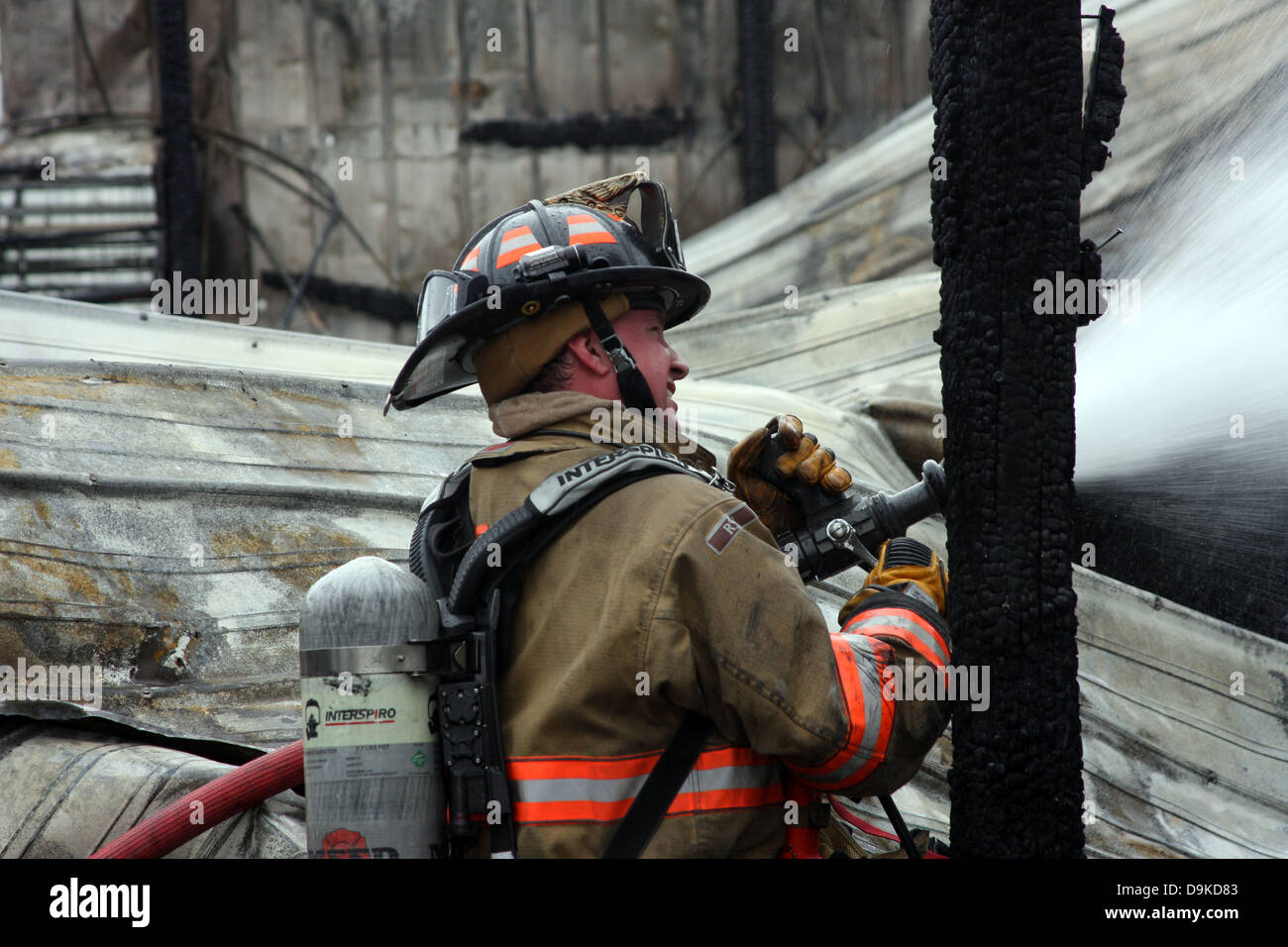 A firefighter pouring water onto a fire Stock Photo Alamy