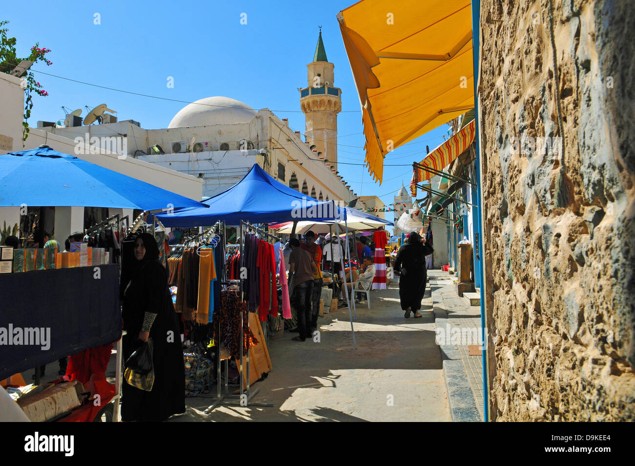 Stalls of street vendors are pictured in the old town of Tripoli, Libya, 8 June 2013. In this area of the Souq, clothing is offered so that it is mostly Libyan women who are the customers buying clothes for their families. In the background, the minaret of the Ahmad Pasha Qaramanli mosque can be seen. Photo: Matthias Tödt Stock Photo