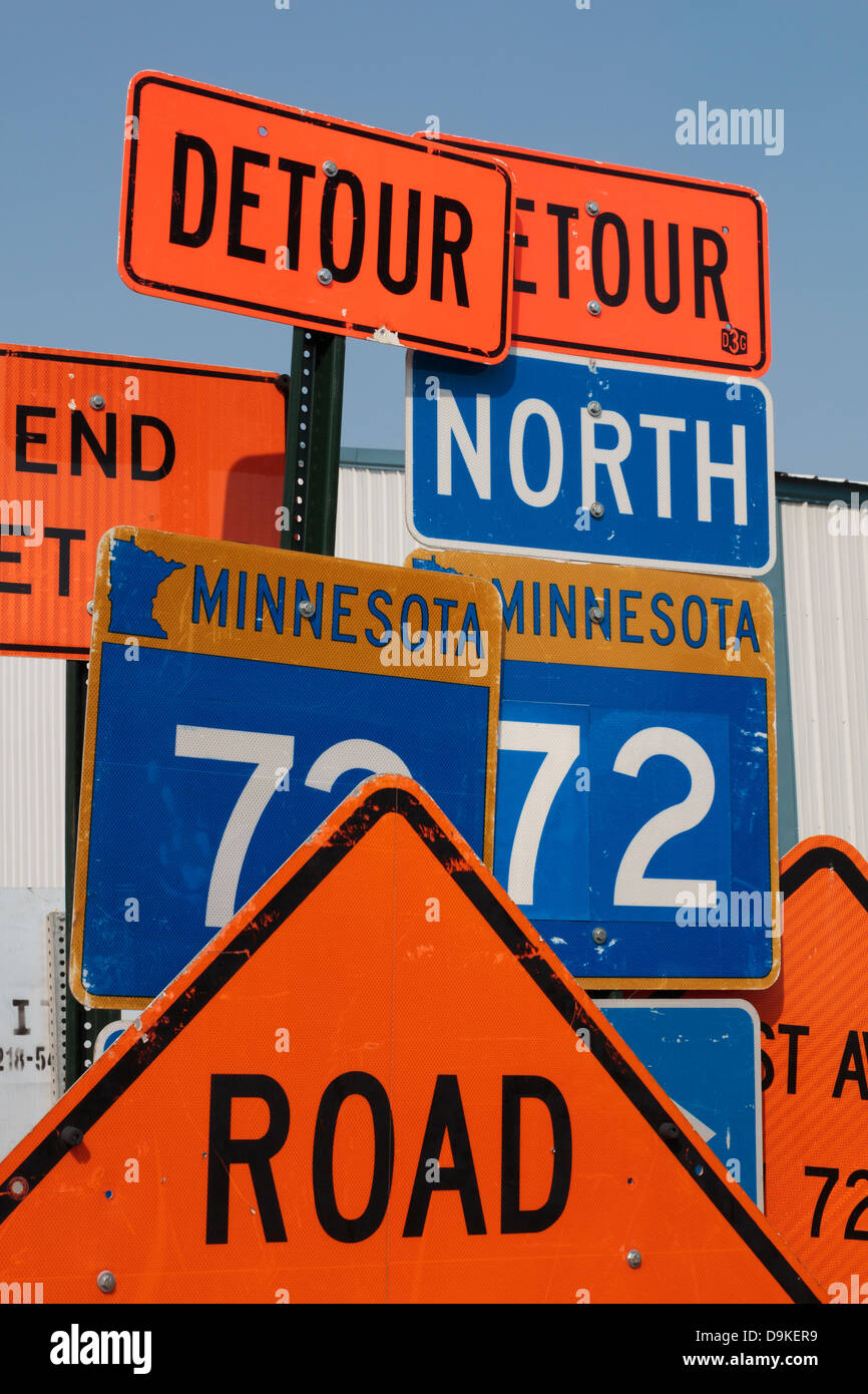 Road construction signs stacked up along the side of a street. Stock Photo