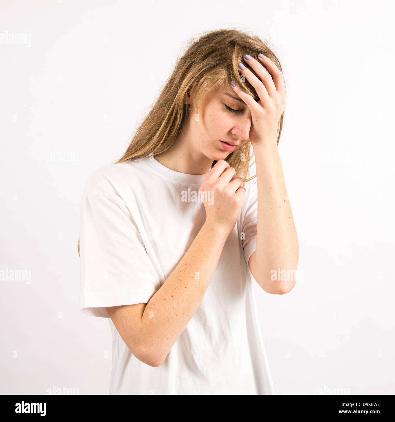 A sad depressed young woman with long blonde hair holding her head in ...