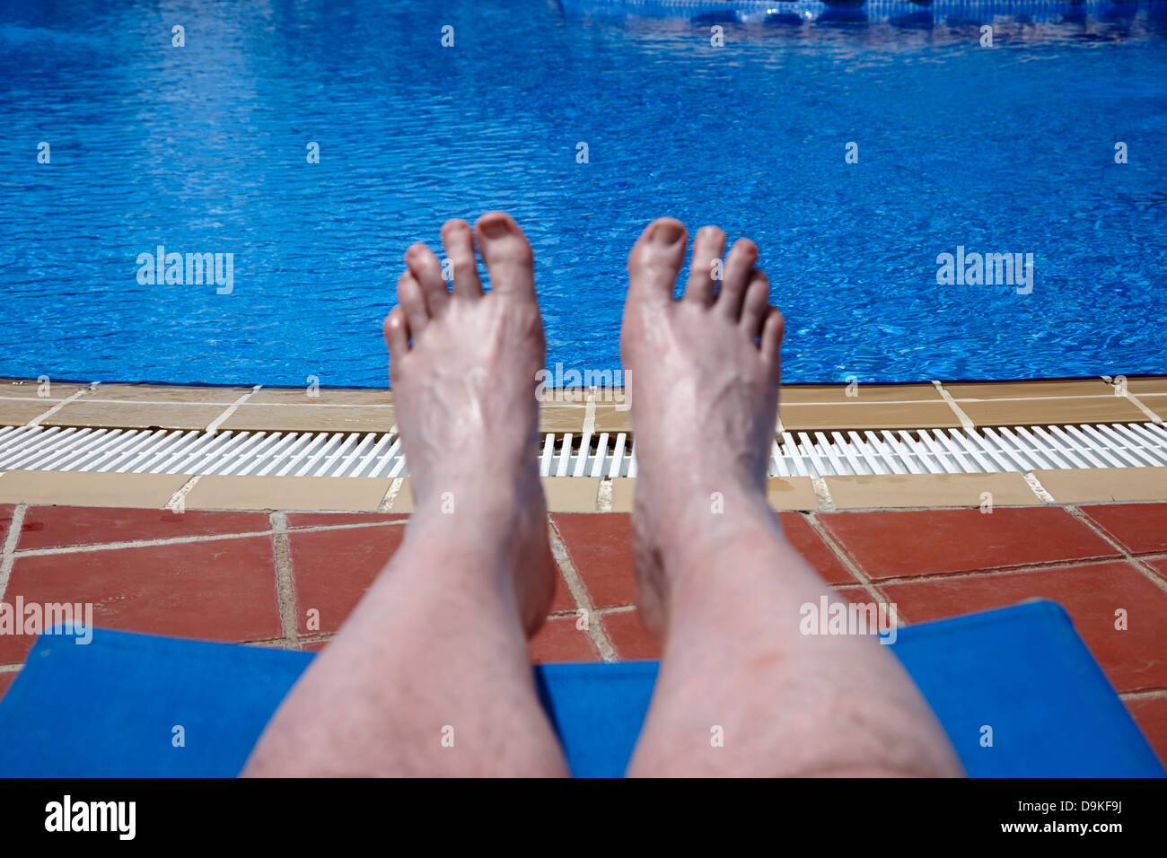 mans feet and legs by the side of a swimming pool on holiday salou costa daurada spain Stock Photo