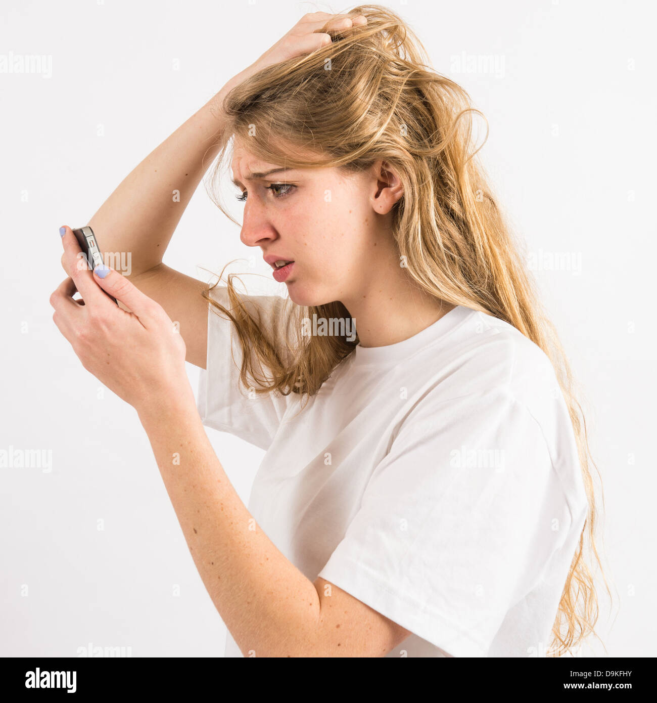 A young woman using an iPhone smart phone looking worried anxious concerned cyber bullying bullied on-line Stock Photo
