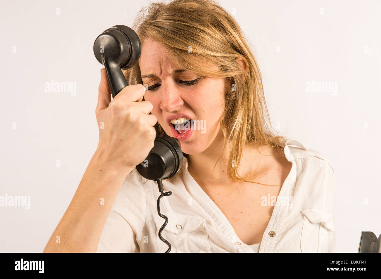 Poor customer service: An angry young woman shouting yelling into an old retro telephone receiver Stock Photo