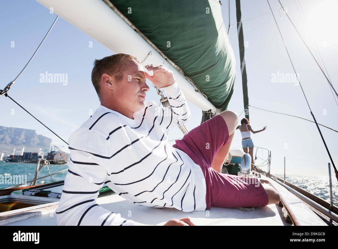 Young man on yacht, shielding eyes Stock Photo