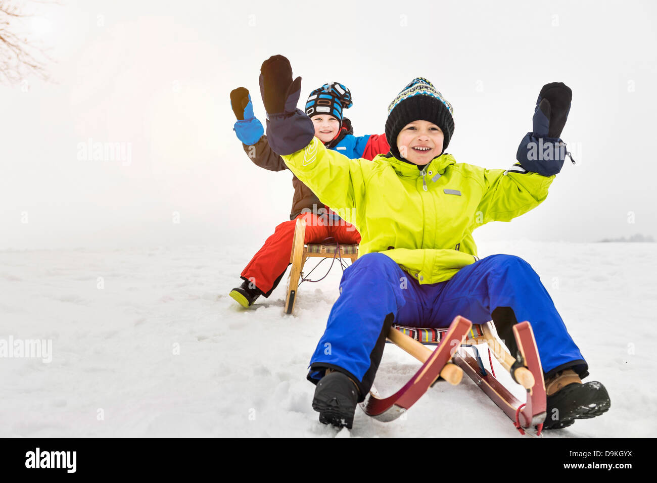 Two boys on toboggans in snow Stock Photo Alamy