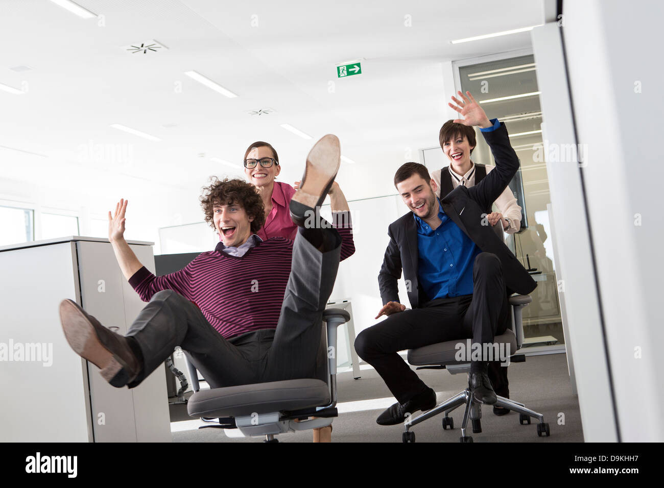 Office workers pushing men on office chairs Stock Photo Alamy