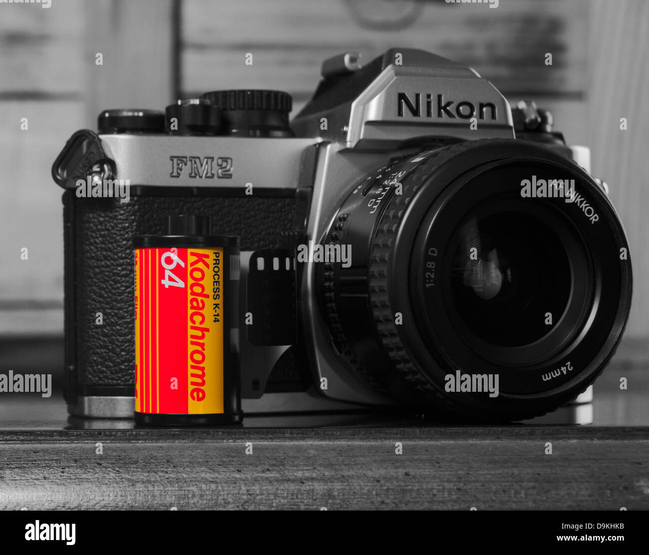 Black and white film photograph of a classic Nikon FM2 35mm camera with a roll of Kodachrome film which has been colorized. Stock Photo