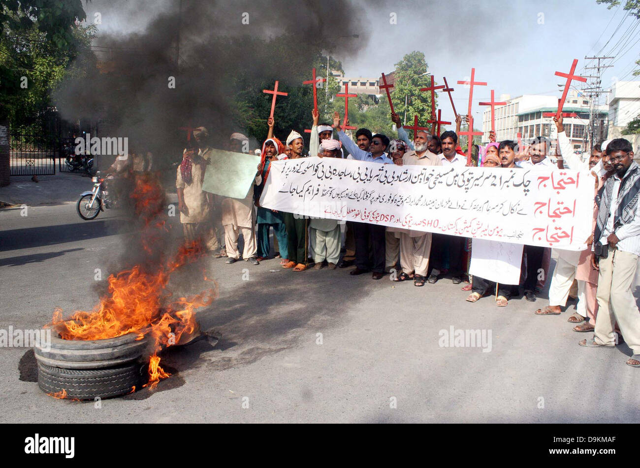 Residents of District Kasur Sadar Pattoki area stand near burning tyres as they are protesting against high- handedness of their area police officials during demonstration arranged by Human Liberation Commission at Lahore press club on Friday, June 21, 2013. Stock Photo