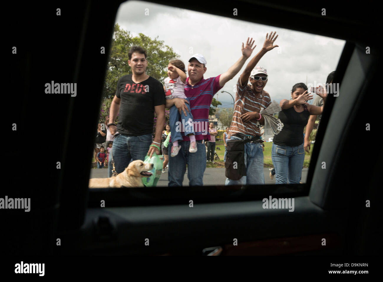 People wave as US President Barack Obama's motorcade passes May 3, 2013 in San Jose, Costa Rica. Stock Photo