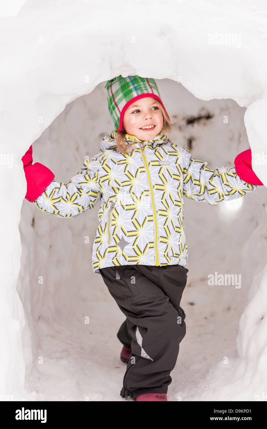 Girl wearing winter clothes standing in igloo Stock Photo
