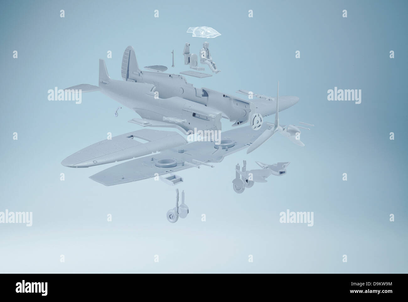 Exploded diagram style photograph of a model Spitfire plane on a blue background Stock Photo