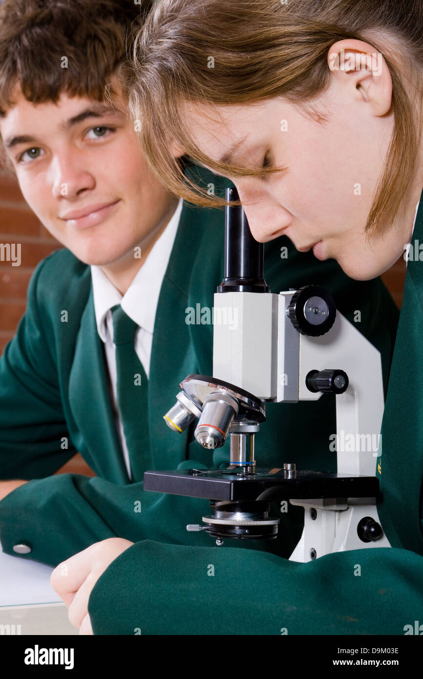 two high school students using microscope in science classroom Stock