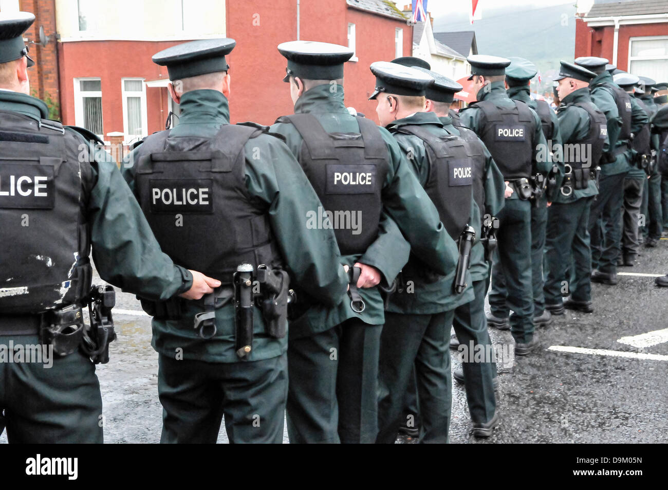 Uniformed PSNI police officers wearing high visibility jackets form a