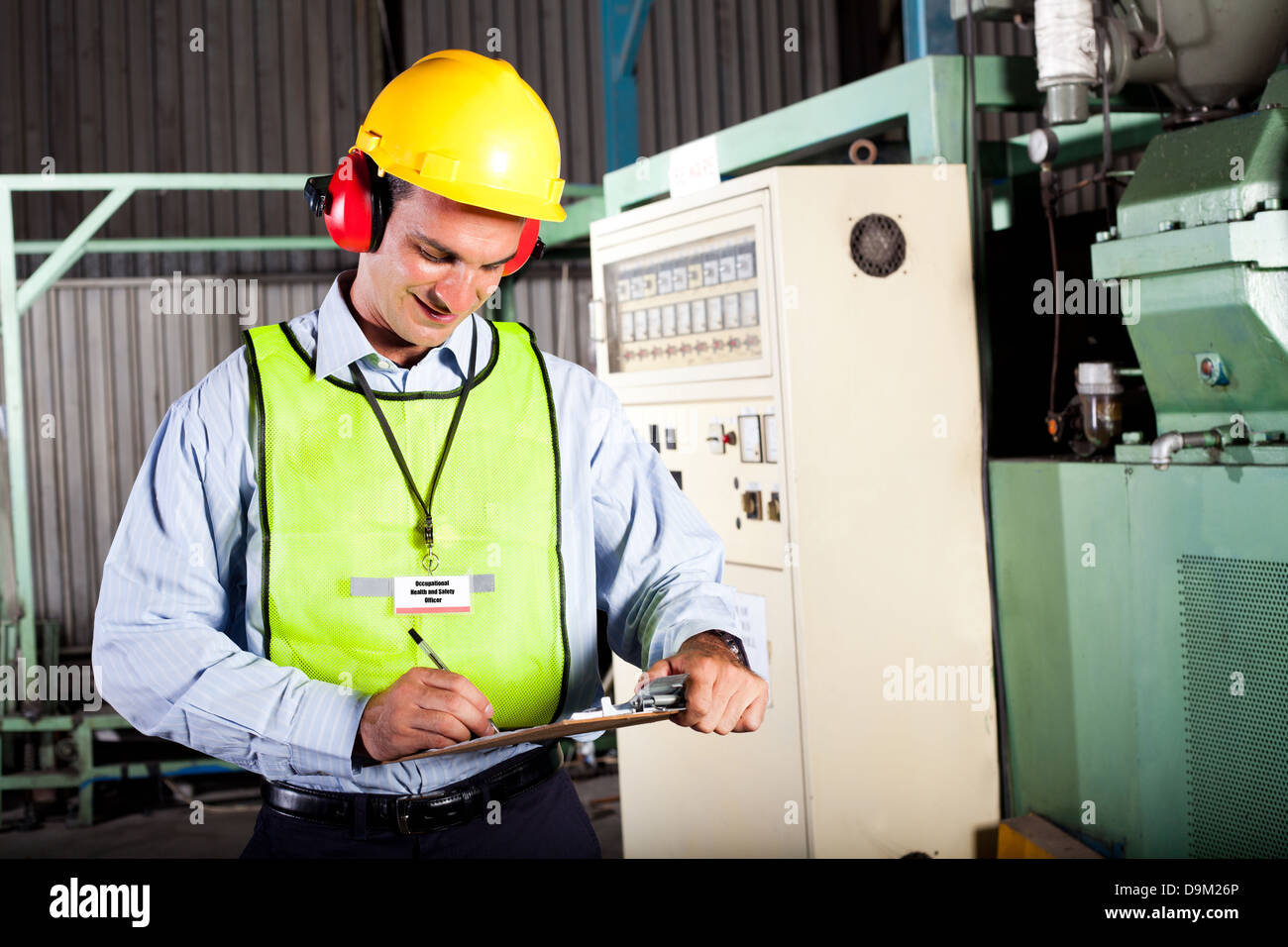 male occupational health and safety officer inside factory doing