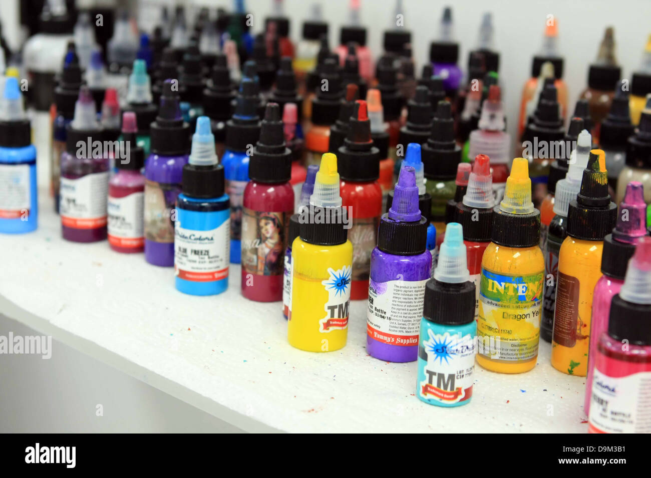 bottles of tattoo ink colors on white shelf Stock Photo
