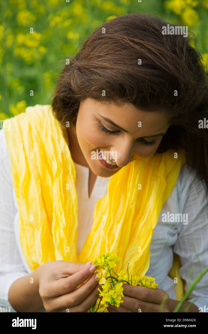 Woman holding mustard flower and smiling Stock Photo